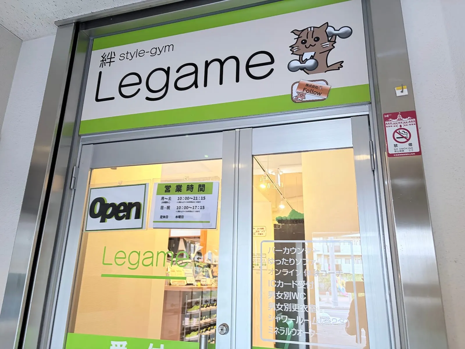 1階入口のガラスドア。「絆 style-gym Legame」の看板と営業時間の掲示、Open の表示