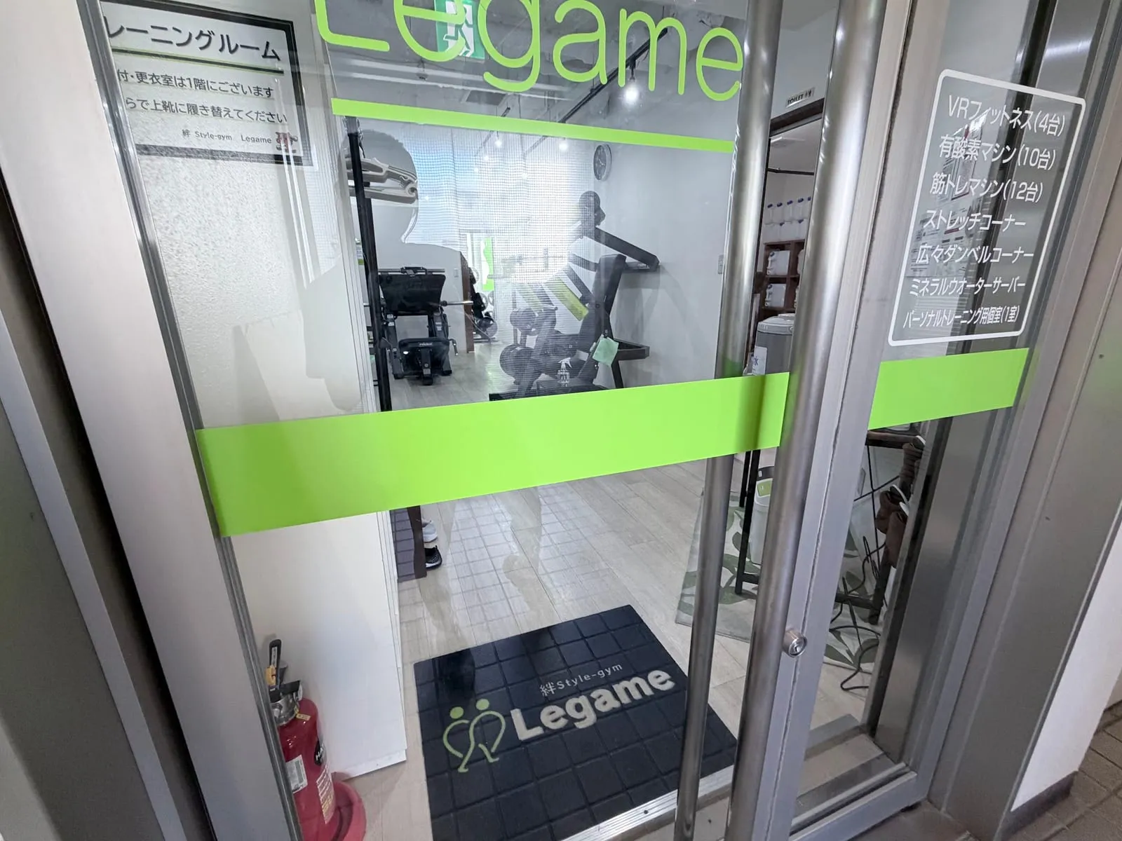 2階トレーニングルームのガラス扉。Legame のロゴと黄緑の帯